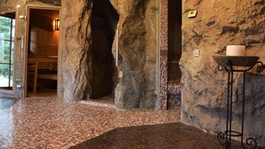 A stone-walled interior with a large archway, tiled flooring, and a candle holder.