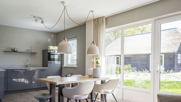 A modern kitchen with a dining area, large windows, and a view of the outdoors. - Bungalow on Texel Near De Slufter Reserve (De Cocksdorp)