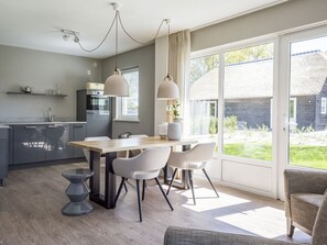 A modern kitchen with a dining area, large windows, and a view of the outdoors. - Bungalow on Texel Near De Slufter Reserve (De Cocksdorp)