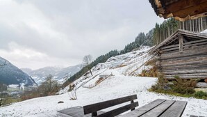 A wooden bench and picnic table on a snow-covered deck with a mountainous backdrop. - Cozy Chalet With Sauna in Grossarl (Grossarl)