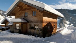 A wooden chalet with a snow-covered roof, situated in a snowy mountainous area. - Cozy Chalet With Sauna in Grossarl (Grossarl)