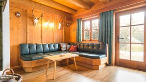 A cozy cabin interior with a wooden ceiling, a leather sofa, a wooden coffee table, and a window with curtains. - Cozy Chalet With Sauna in Grossarl (Grossarl)