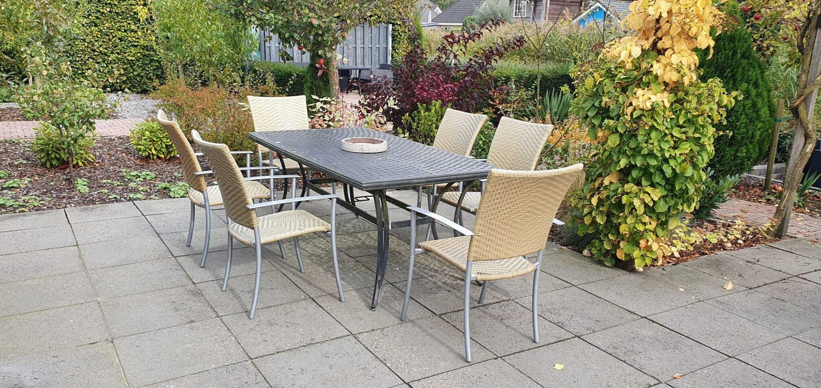 An outdoor patio with a rectangular table and six wicker chairs.