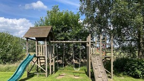 A wooden playground structure with a slide, swings, and a climbing net. - Pet-friendly Mansion (Swolgen)