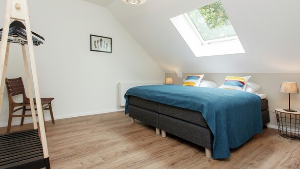 A bedroom with a skylight, a bed with blue bedding, a wooden ladder, a chair, and a framed picture on the wall. - Pet-friendly Mansion (Swolgen)