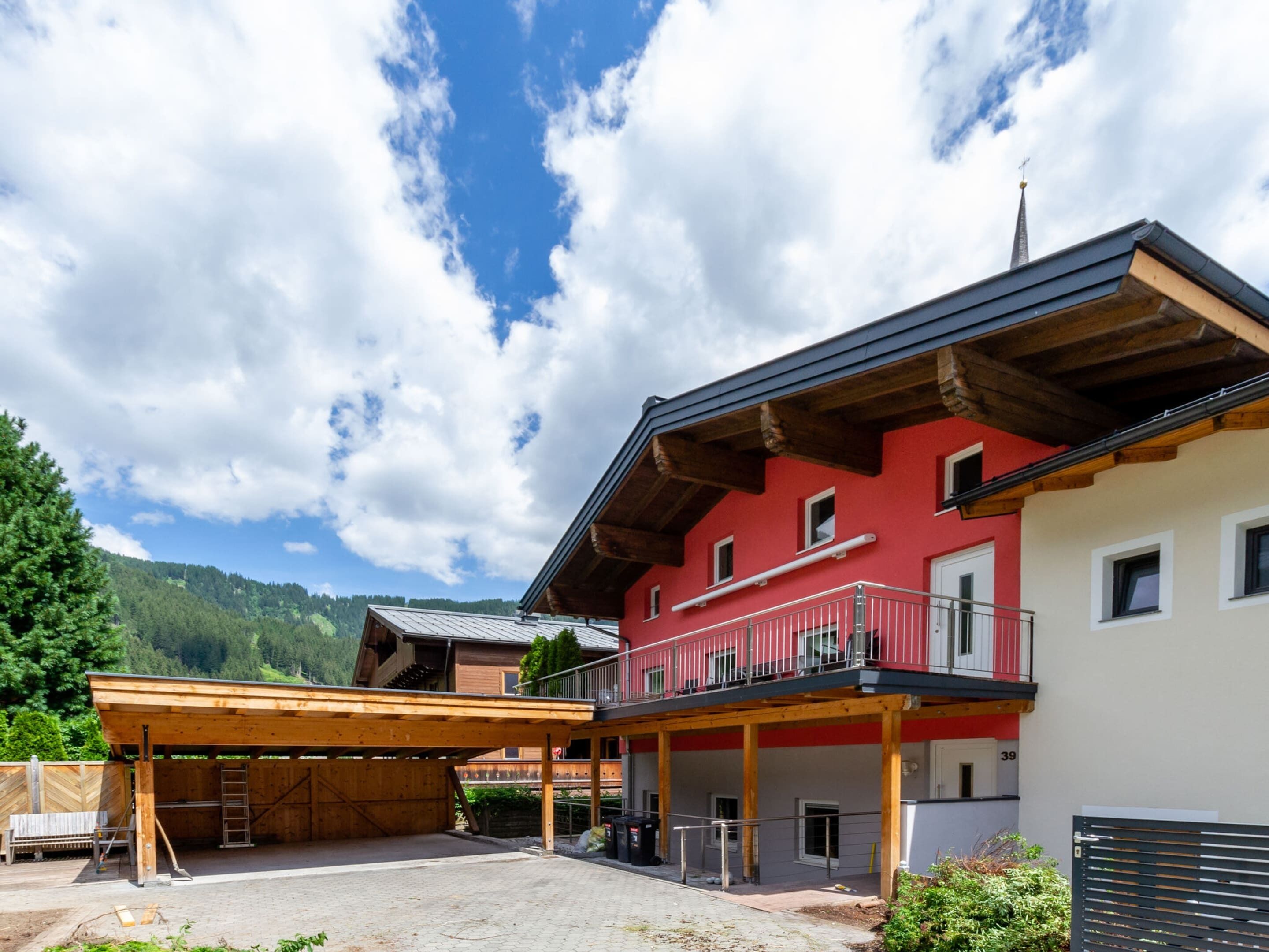Ein rotes und weißes Gebäude mit Balkon, Holzbauweise und Blick auf eine Berglandschaft.