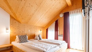 A wooden room with a bed, a bench, and a window with curtains. - Luxurious Chalet in Murau with Outside Hot Tub (Murau)