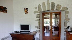 Ein Zimmer mit einem Steingewölbe, einem Holztisch mit einem Computer und Blick durch eine Glastür.