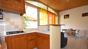 Eine Küche mit Holzausstattung, einem Gasherd, einem Spülbecken und einem Fenster mit Vorhängen.