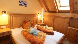 A cozy wooden room with a high ceiling and a skylight, featuring a bed with patterned bedding and a nightstand with a lamp. - Quaint Apartment in Langenfeld (Laengenfeld)