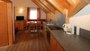 A cozy kitchen with wooden beams, a dining area with chairs, a TV, and a window with curtains. - Quaint Apartment in Langenfeld (Laengenfeld)