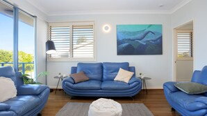 Ein modernes Wohnzimmer mit einem blauen Sofagarnitur, einem runden Couchtisch und einem Bild an der Wand.