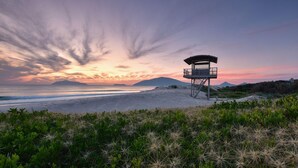 Ein Rettungsturm am Strand, im Hintergrund ein Sonnenuntergang.