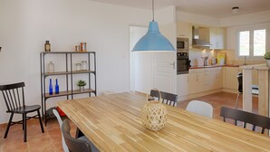 Eine moderne Küche mit weißen Schränken, einem Holzesstisch und einer blauen Pendelleuchte.