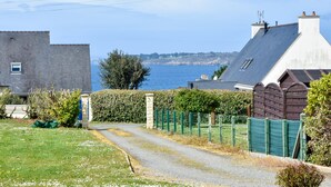 A coastal residential area with a gravel driveway leading to a house with a sloped roof and a visible chimney. - Seaside Villa With Pool in Moelan (Moelan-sur-Mer)