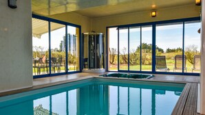 An indoor swimming pool with clear glass walls, a hot tub, and a view of the outdoors. - Seaside Villa With Pool in Moelan (Moelan-sur-Mer)