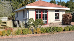 Un petit bâtiment d’un seul étage, avec un toit recouvert de tuiles rouges, une façade blanche et une porte à cadre rouge.
