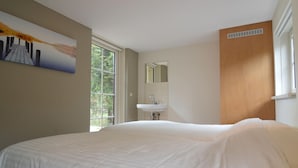 Une chambre avec un grand lit, une fenêtre, un lavabo et un miroir.