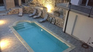 A rectangular swimming pool with a stone border, surrounded by lounge chairs and a stone wall. - Villa Ada - Rebomaholidays (Tignale)