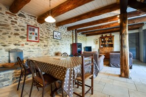 A stone-walled room with a wooden ceiling, a dining table with a polka dot tablecloth, and a fireplace. - Holiday Home With Private Terrace (Saint-Beauzire)