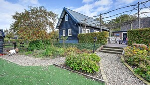 A residential house with a blue exterior, a gravel driveway, and a green lawn. - Holiday Home in Overberg With Garden and Terrace (Overberg)