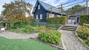 A traditional blue house with a sloped roof, surrounded by a well-maintained garden with a gravel path leading to the entrance. - Holiday Home in Overberg With Garden and Terrace (Overberg)