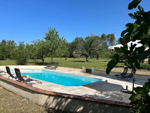 A swimming pool with lounge chairs, surrounded by a grassy area and trees. - Holiday Home in Villecroze With Pool & Garden (Villecroze)