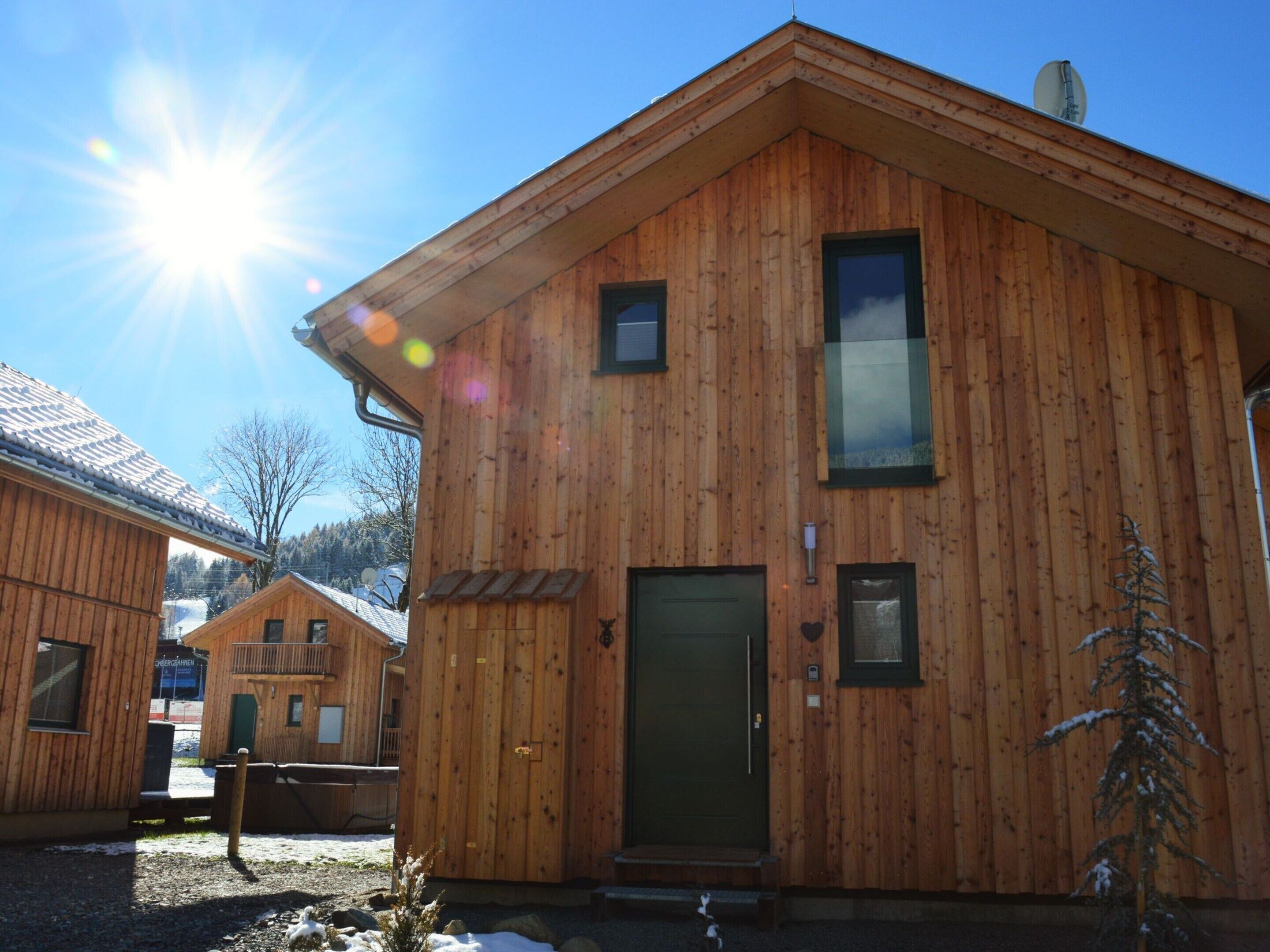 A wooden cabin with a green door, a small window, and a satellite dish on the roof.