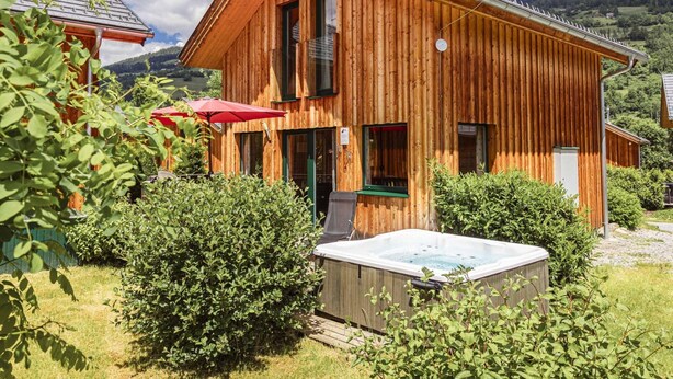 A wooden cabin with a hot tub, surrounded by greenery and a mountainous backdrop. - Chalet With Outdoor hot tub (Sankt Georgen am Kreischberg)