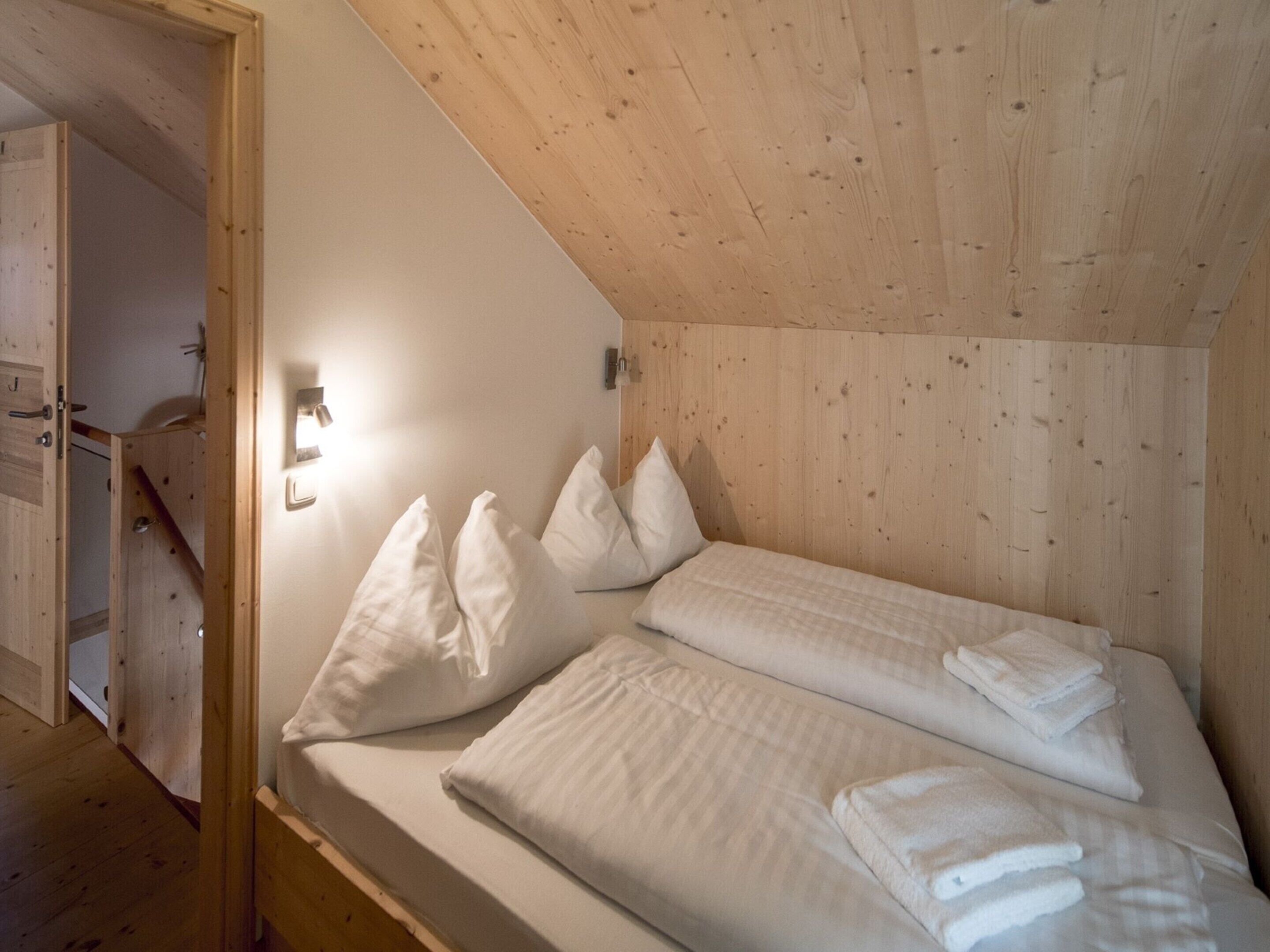 A bedroom with two beds, wooden walls, and a sloped ceiling.