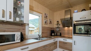 A modern kitchen with wooden cabinets, a built-in microwave, a coffee maker, and a refrigerator. - Chalet With Outdoor hot tub (Sankt Georgen am Kreischberg)