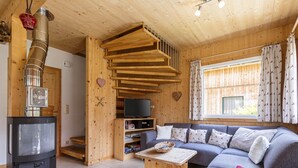A cozy wooden cabin interior with a fireplace, a sofa, a television, and a window with curtains. - Chalet With Outdoor hot tub (Sankt Georgen am Kreischberg)