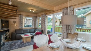 A cozy wooden interior with a sofa, dining table set for four, and a TV. - Chalet With Outdoor hot tub (Sankt Georgen am Kreischberg)