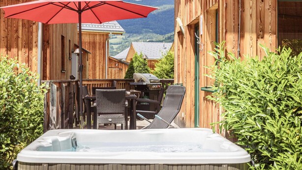 A wooden cabin with a hot tub, outdoor seating, and a mountain view. - Chalet With Outdoor hot tub (Sankt Georgen am Kreischberg)