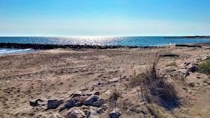 Ein Strand mit felsiger Küste und blauem Himmel.