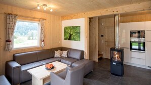 A modern log cabin interior with a wooden interior, a sofa set, a dining table, a fireplace, and a kitchen area. - Chalet With Whirlpool tub (Sankt Georgen am Kreischberg)