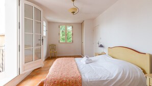 Une chambre à coucher avec un lit, une chaise, une fenêtre et une porte.