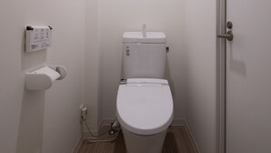 A small, white bathroom with a toilet, a wall-mounted sink, and a door. - Ginza Tsukiji GUEST HOUSE 301. (Chuo)