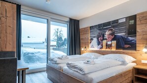 A modern bedroom with a large bed, wooden headboard, and a view of a snowy landscape through a large window. - Cozy Holiday Home in Mauterndorf near Ski Area (Mauterndorf)