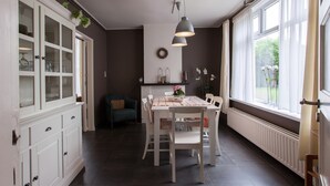 A dining area with a white table and chairs, a hanging light fixture, and a view through large windows. - From the Zealand Coast and Near Brugge (Aardenburg)