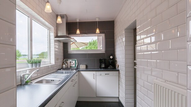 A compact kitchen with white cabinets, a black countertop, and pendant lighting. - From the Zealand Coast and Near Brugge (Aardenburg)