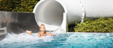 A child sliding down a water slide into a pool.