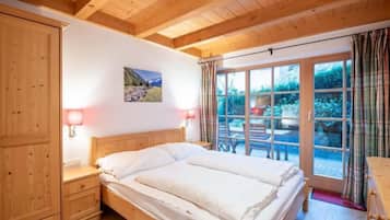 Ein Schlafzimmer mit einem hölzernen Bett, einem Nachttisch, einer Wandlampe und einem Fenster mit Vorhängen.