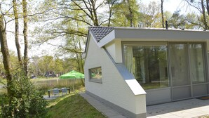Un bâtiment moderne doté de grandes fenêtres, d’un toit en pente et d’une zone pavée devant l’entrée.