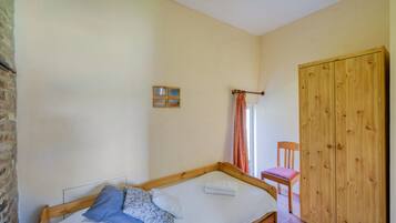 A bedroom with a wooden bed, a wooden wardrobe, and a small chair.