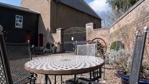 Un patio con una mesa redonda de metal, un edificio de ladrillo y una reja.
