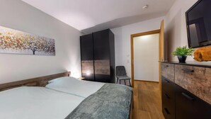 Een slaapkamer met een bed, een kledingkast, een stoel en een televisie.