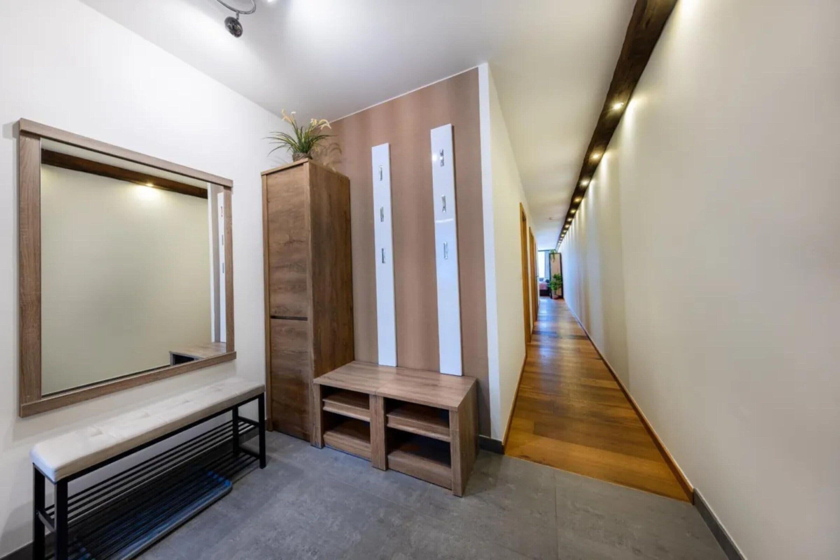A hallway with a bench, a mirror, and a wooden panel with vertical elements.