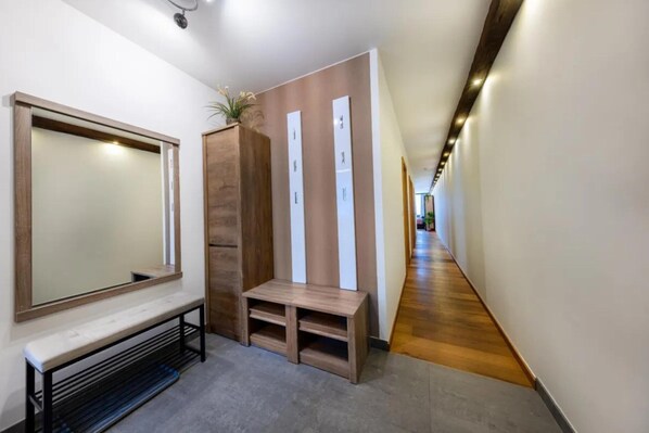 Un couloir avec un banc, un miroir et un panneau en bois orné d’éléments verticaux.