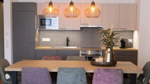 Een moderne keuken met een houten eettafel, vier stoelen en hanglampen.
